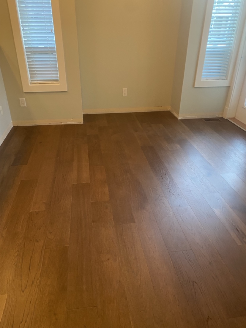 Bright room with a warm medium-brown plank floor and windows, installed by Hearth & Plank