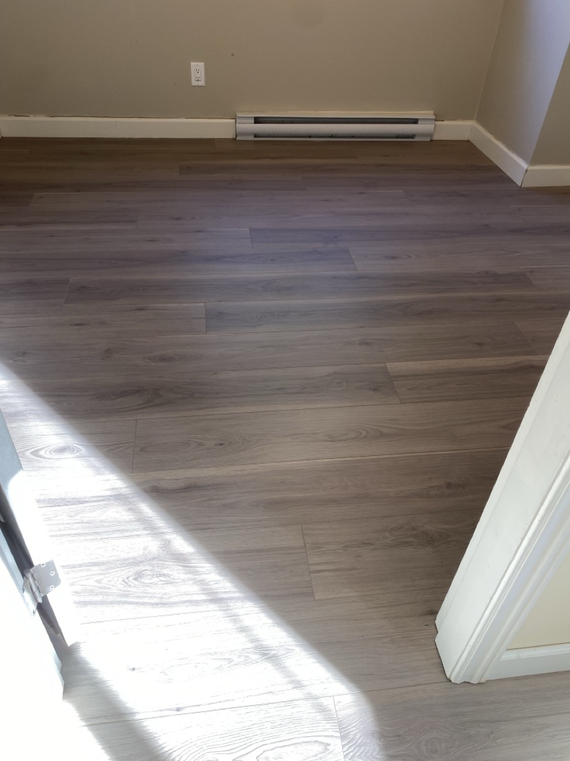 Empty bedroom with a warm grey-brown plank floor installed by Hearth & Plank