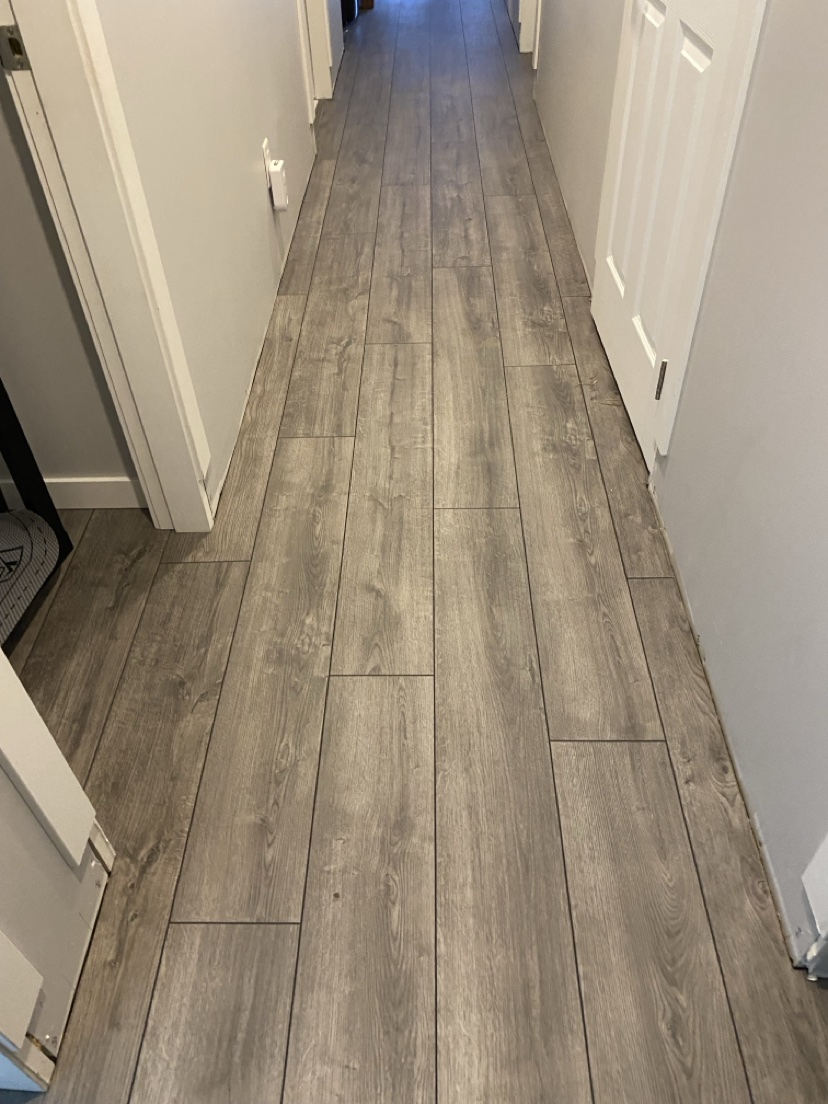 Hallway with a grey-brown plank floor installed by Hearth & Plank