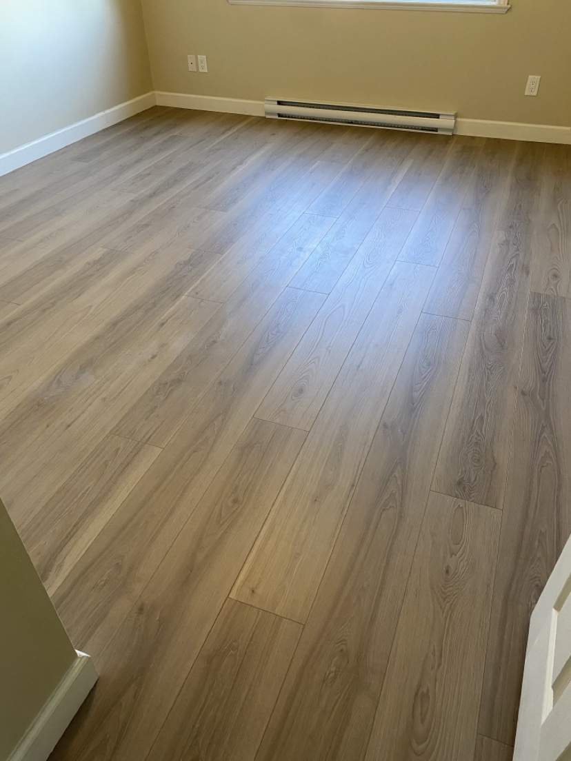 Bedroom with a light natural plank floor installed by Hearth & Plank