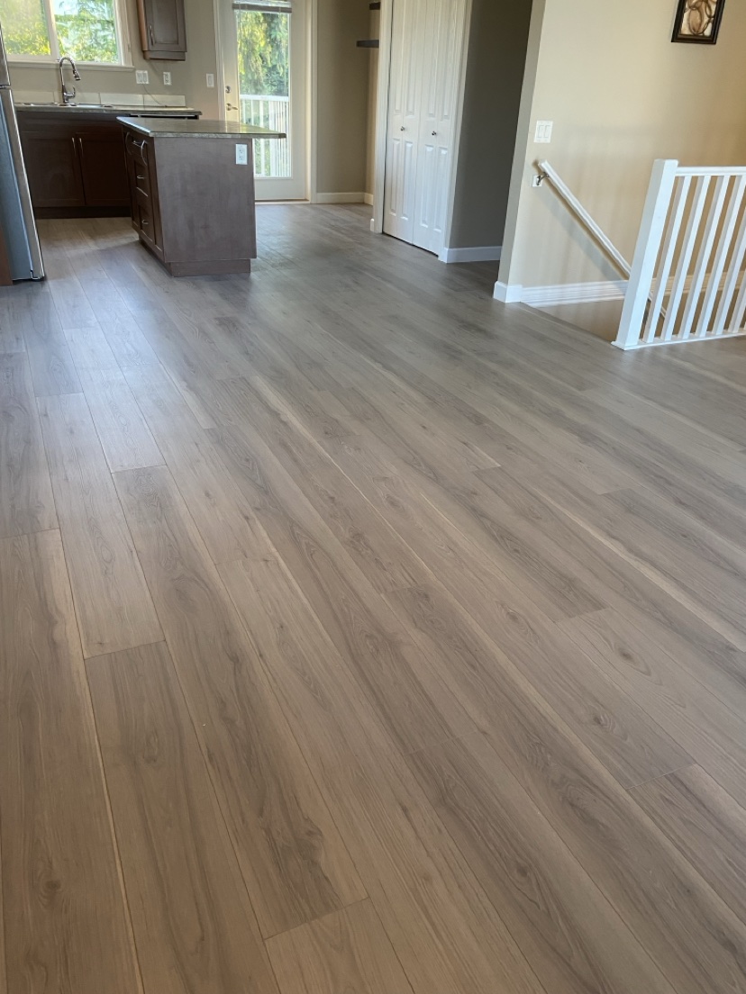 Open-plan kitchen and living room with a light grey-brown plank floor installed by Hearth & Plank